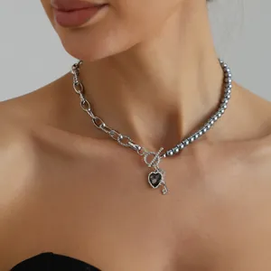 Primer plano de un collar plateado con perlas grises y colgante en forma de corazón