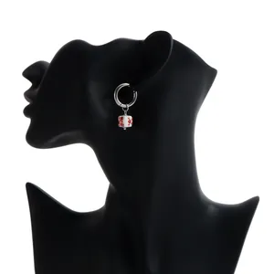 Macro view of a silver hoop earring featuring a white square ceramic bead with red flowers