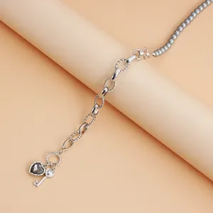 Detalle de collar de perlas grises con colgantes de corazón negro y llave plata.