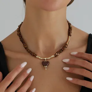 Detail shot of a Maillard coffee beaded necklace with a golden lava heart pendant for women.
