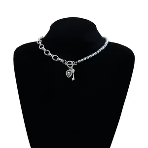 Vista detallada de un collar con corazón de diamante negro, dije de llave y perlas elegantes