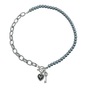 Collar elegante con perlas grises, cadena plateada, colgantes de corazón negro y llave.