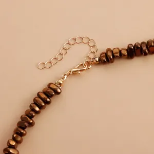 Detailed close-up of brown beaded necklace with gold-tone lobster clasp and extender chain