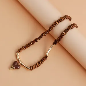 Detailed view of the brown beaded necklace featuring a gold lava-textured heart pendant