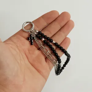 Llavero de cruz con cuentas negras multicapa y cadenas de metal plateado brillante.