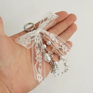 Primer plano detallado de elegante llavero con lazo de encaje, perlas y diamantes