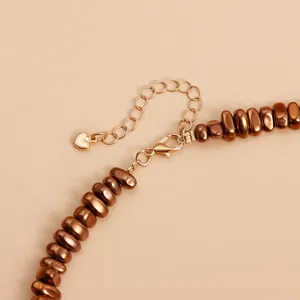 Detailed view of coffee-colored lava beads and gold heart charm on a retro style necklace