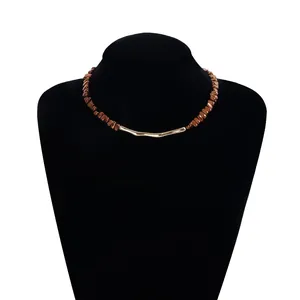 Detailed view of a brown beaded necklace with a gold-tone metallic bar centerpiece
