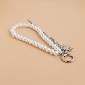 Primer plano de un elegante llavero de perlas y cadena de plata con colgante de sol