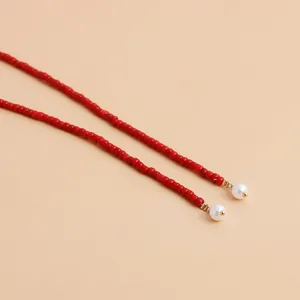 Close-up detail of a Y2K style long red seed bead necklace with elegant white pearl drops