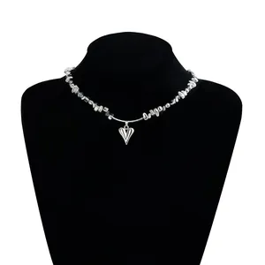 Gros plan d'un collier avec pendentif en cœur argenté et perles irrégulières sur buste