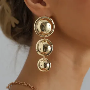 Detailed view of retro triple-tiered gold-toned circular drop statement earrings