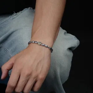 Detaillierte Makroansicht eines Kaffeebohnen-Perlenarmbands für Herren mit Silberkreuz
