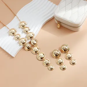 Detailed view of bold gold geometric Y-shaped necklace and matching circular drop earrings
