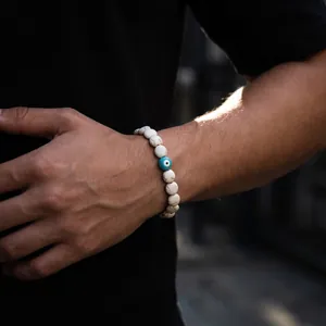 A close-up shot showing the texture of a white beaded evil eye bracelet on a wrist