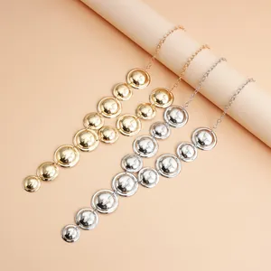 Close-up of statement Y-shaped necklaces with metallic geometric discs in gold and silver