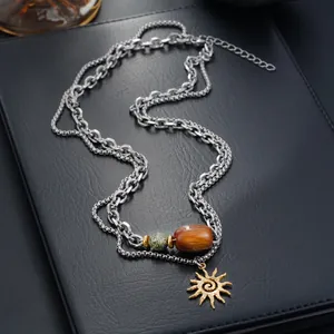 Gros plan d'un collier à deux rangs avec pendentif soleil et perles de marbre sur cuir.