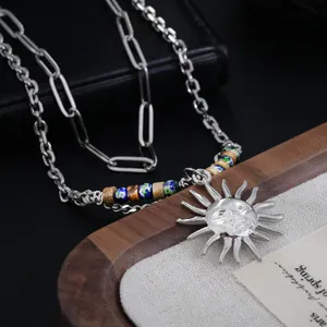 Détail d'un collier à double épaisseur avec pendentif soleil et perles