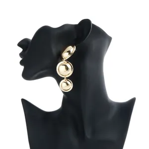 Macro shot of oversized vintage gold geometric triple-drop earrings on black mannequin