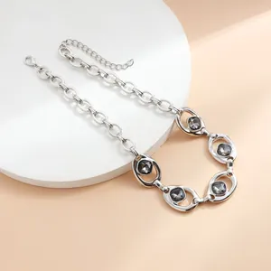 Primo piano di una collana a catena d'argento con inserti di cristalli grigio scuro.