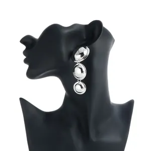 Detailed view of silver tiered domed geometric earrings on a black bust