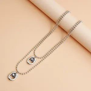 Primo piano della collana a Y argento con pendenti irregolari e pietre grigie.