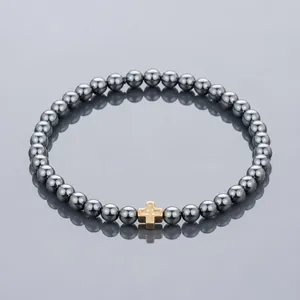 Detailansicht eines gunmetal Perlenarmbands mit einem goldfarbenen Kreuz-Mittelstück.
