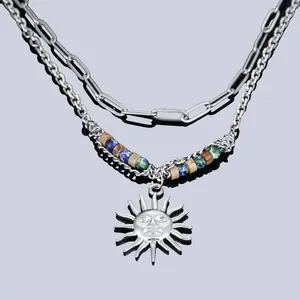 Gros plan d'un collier à deux rangs avec un pendentif soleil et des perles colorées.