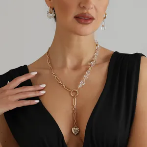 Close-up detail of a vintage gold heart pendant crystal necklace and earring set on a model