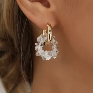 Detail shot of gold-plated hoop earrings with irregular clear crystal beads on ear.