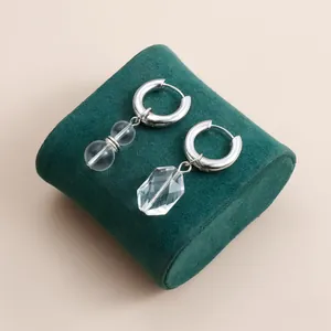 Detailed view of silver hoop earrings with clear crystal drop and double sphere charms