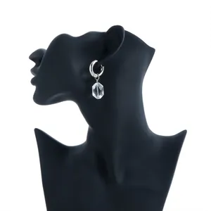 Silver hoop earrings with a faceted clear crystal drop on a black jewelry bust