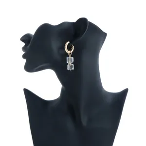 Detailed view of elegant gold hoop earrings with clear square crystal drops on mannequin