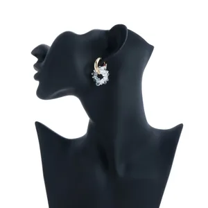 Close-up of gold hoop earring with clear crystal flower cluster on black mannequin
