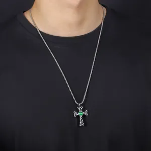 Close-up of a titanium steel Celtic knot cross necklace with a green stone on a model.