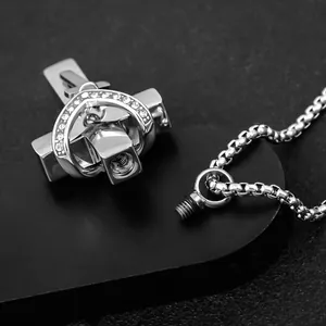 Macro detail of the screw-top mechanism on a polished silver cross heart pendant