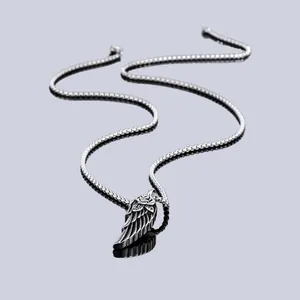 Detailed macro view of a silver stainless steel wing pendant featuring a rose engraving