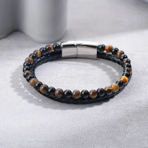 Close-up detail of braided leather bracelet with tiger eye beads and steel clasp.