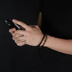 Close-up detail of tiger eye stone bead and braided leather double-layer bracelet on male wrist.