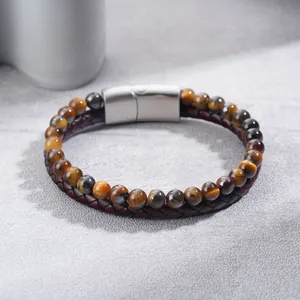 Macro detail of natural tiger eye stone beads and braided leather bracelet with magnetic clasp.
