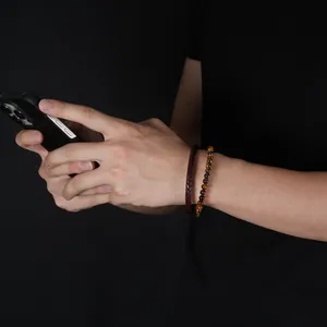 Detail view of a stylish men's tiger eye bead and braided leather bracelet set on wrist