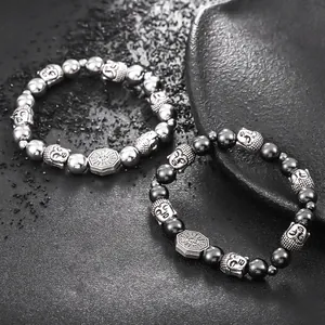 Detalle de pulseras de cuentas plateadas y negras con cabezas de Buda y amuletos de Bagua