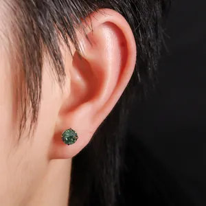 Primer plano de un pendiente de titanio F136 con circón verde de corte rosa en la oreja