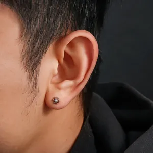 Close-up of F136 titanium snowflake stud earring worn on a male ear lobe
