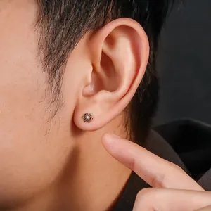 Close-up of a titanium snowflake stud earring with a central zircon on a male ear