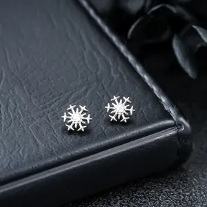 Close-up of F136 titanium snowflake stud earrings with sparkling zircon centers.