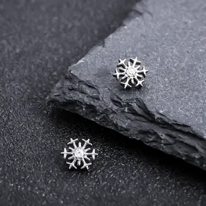 Macro detail showing the intricate snowflake design and central zircon of the titanium stud.