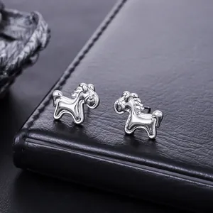 Macro detail of minimalist silver horse shaped stud earrings with polished finish on leather