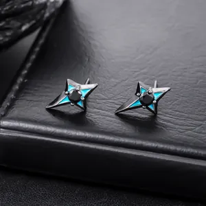 Detail macro shot of black four-pointed star stud earrings with blue enamel accents