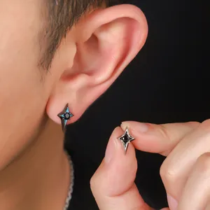 Close-up detail of stylish black zirconia four-pointed star stud earrings worn on ear